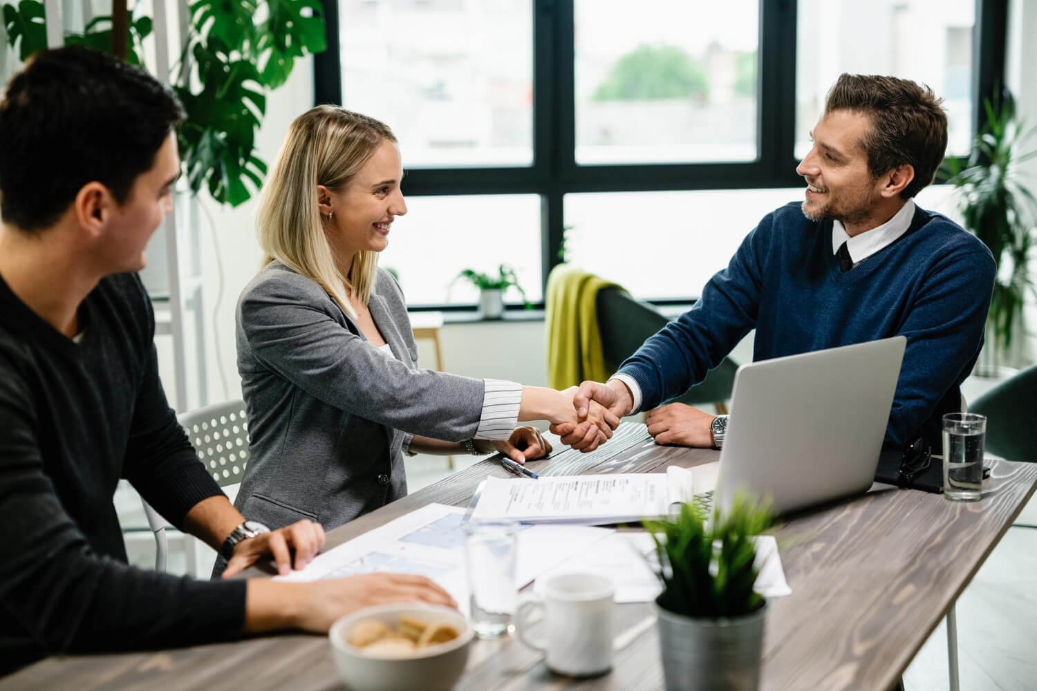 young happy couple meeting with financial advisor office woman is handshaking with agent